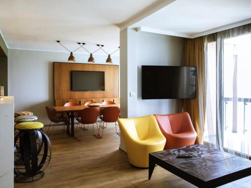 a living room with a television and a table and chairs at Pullman Dakar Teranga in Dakar