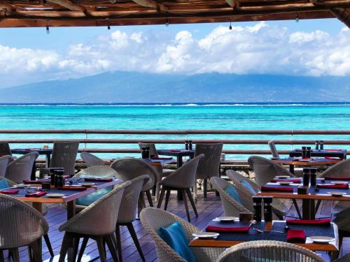 a restaurant with tables and chairs in front of the ocean at Sofitel Kia Ora Moorea Beach Resort in Maharepa