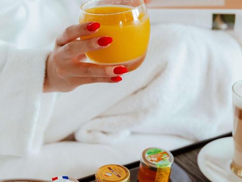 a woman holding a glass of orange juice at Pullman Toulouse in Blagnac
