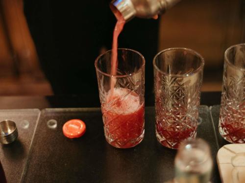 a drink being poured into two glasses on a table at Pullman Toulouse in Blagnac