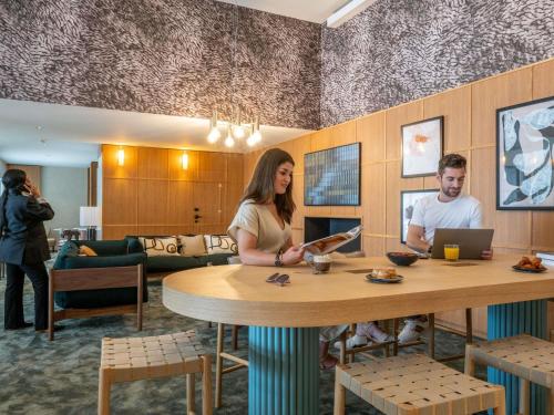 a rendering of a lobby with a man and woman sitting at a table at Mercure La Rochelle Vieux Port in La Rochelle