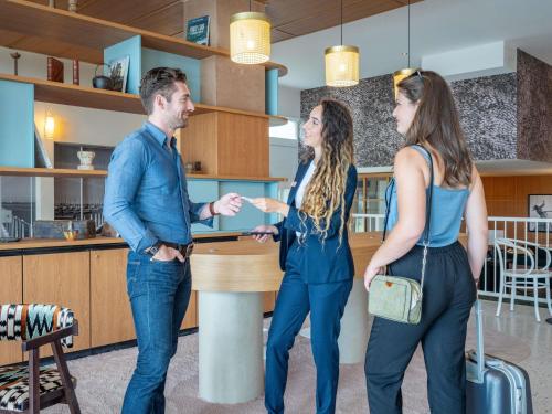 a man and two women standing at a counter in a store at Mercure La Rochelle Vieux Port in La Rochelle