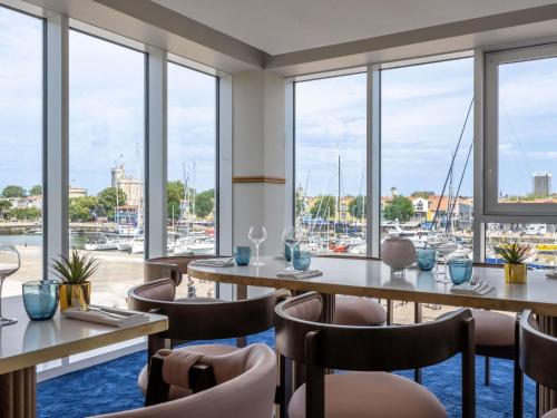 a restaurant with tables and chairs and a marina at Mercure La Rochelle Vieux Port in La Rochelle