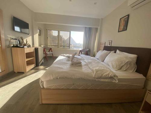 a bedroom with a large white bed with a window at Zlato Pyramids View INN in Cairo