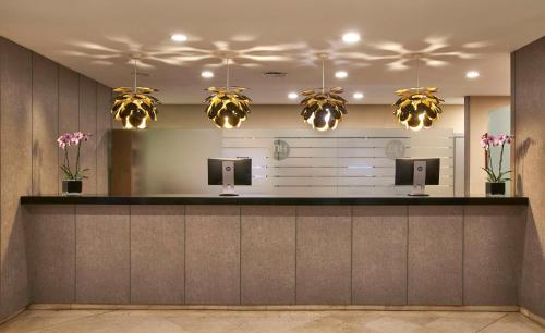 a lobby with a reception counter with pendant lights at NH Ciudad de Valencia in Valencia