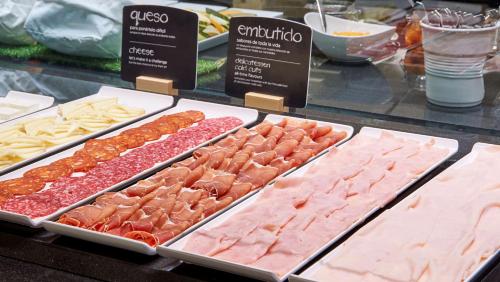 a display case with different types of meats and cheese at NH Ciudad de Valencia in Valencia