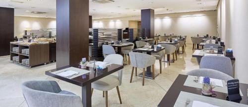 a restaurant with tables and chairs in a room at NH Ciudad de Valencia in Valencia