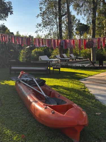 a red kayak sitting on the grass in a park at Al Natural Posada in Nueva Palmira