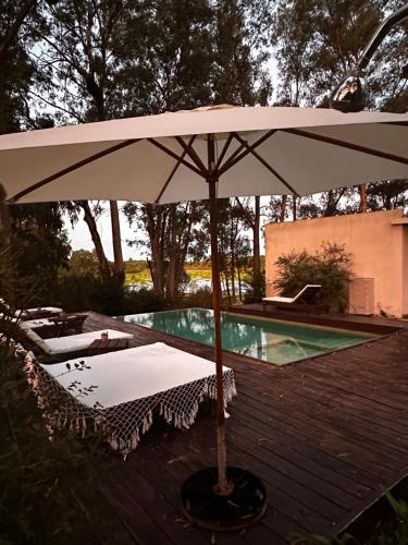 an umbrella sitting on a deck next to a swimming pool at Al Natural Posada in Nueva Palmira
