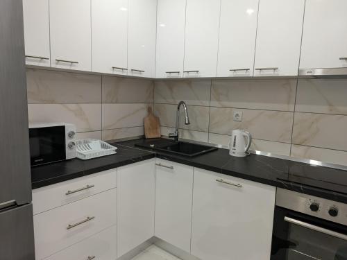 a kitchen with white cabinets and a sink and a microwave at Apartman Lukić Bratunac in Bratunac