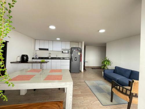 uma cozinha e sala de estar com uma mesa e um sofá azul em Confortable Hospedaje- Ubicación Estratégica Bogotá em Bogotá