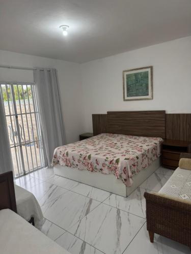 a bedroom with a bed and a large window at Casa em Guaratuba com piscina in Guaratuba