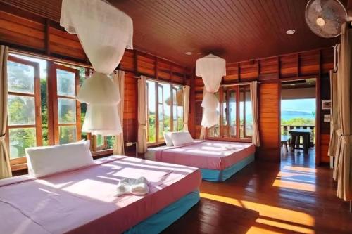 Dos camas en una habitación con ventanas. en Koh Phaluay Eco Resort, 