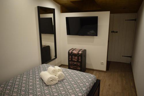 a bedroom with towels on a bed with a television at Casa do Chico in Mértola