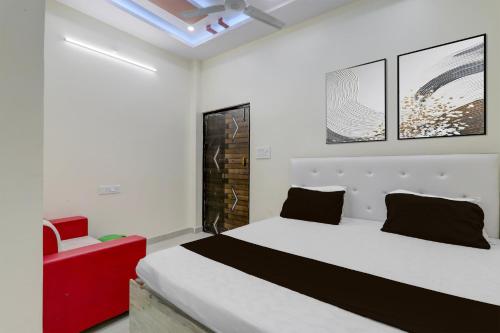 a bedroom with a white bed and a red chair at SPOT ON Kanhaiya Hotel in Lucknow