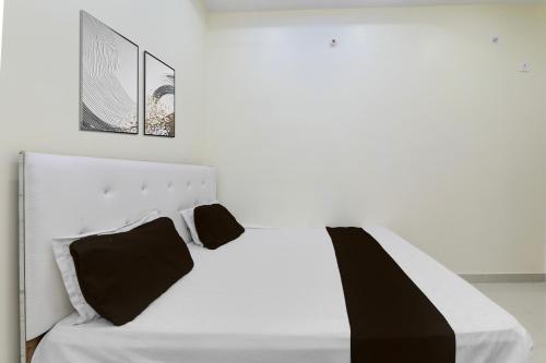 a white bed with two black pillows on it at SPOT ON Kanhaiya Hotel in Lucknow