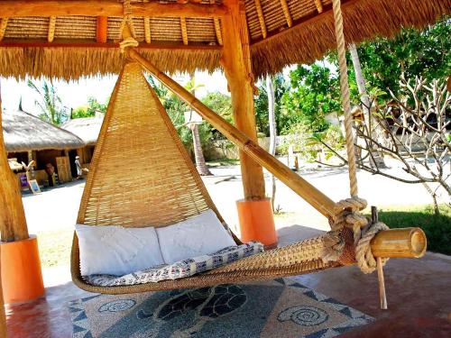 a hammock hanging from a straw umbrella at Novotel Lombok Resort & Villas in Kuta Lombok