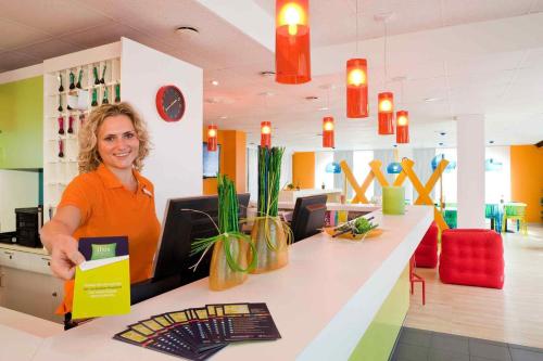a woman sitting at a counter in a store at ibis Styles Duesseldorf-Neuss in Neuss
