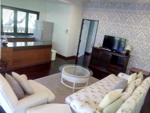 a living room with a couch and a tv at Coco Palm Beach Resort - SHA Extra Plus in Mae Nam