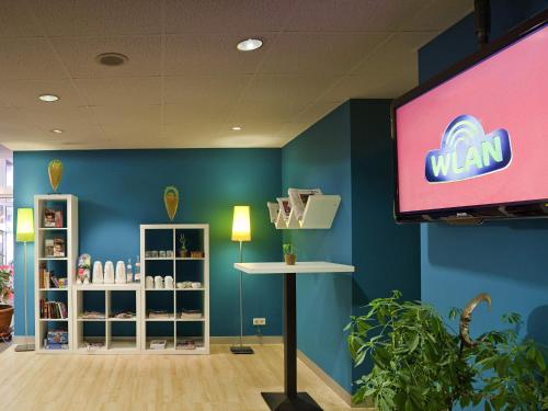 a room with a tv and a blue wall at ibis Styles Duesseldorf-Neuss in Neuss