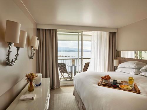 a hotel room with a bed with a tray of food on it at Sofitel Golfe d'Ajaccio Thalassa Sea & Spa in Ajaccio