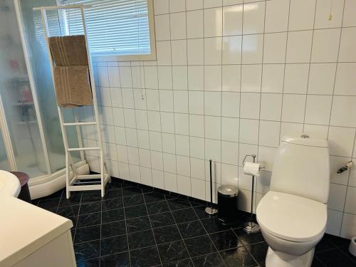 een badkamer met een toilet en een betegelde muur bij Koselig hus i Svolvær i Lofoten med elbil-lader in Svolvær