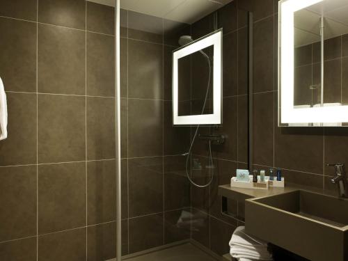a bathroom with a shower and a sink and a mirror at Novotel Metz Centre in Metz