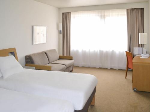 a hotel room with a bed and a couch at Novotel Metz Centre in Metz