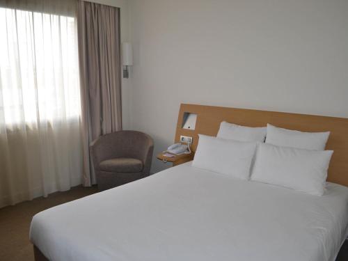 a hotel room with a large bed and a chair at Novotel Metz Centre in Metz