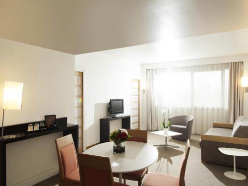 a living room with a couch and a table and chairs at Novotel Metz Centre in Metz