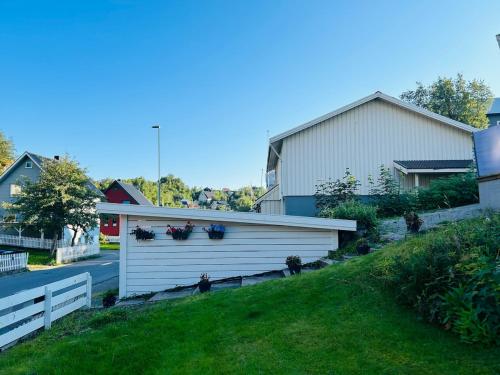 een witte garage met bloemen erop naast een huis bij Koselig hus i Svolvær i Lofoten med elbil-lader in Svolvær
