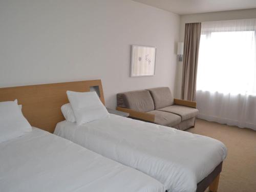 a hotel room with two beds and a couch at Novotel Metz Centre in Metz