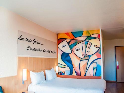 a bedroom with a painting on the wall next to a bed at ibis Montpellier Centre Comedie in Montpellier