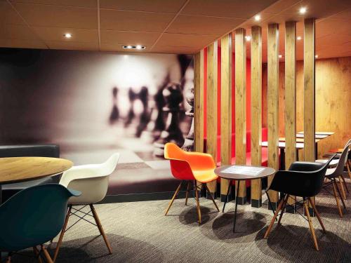 a restaurant with tables and chairs and a painting at ibis Montpellier Centre Comedie in Montpellier
