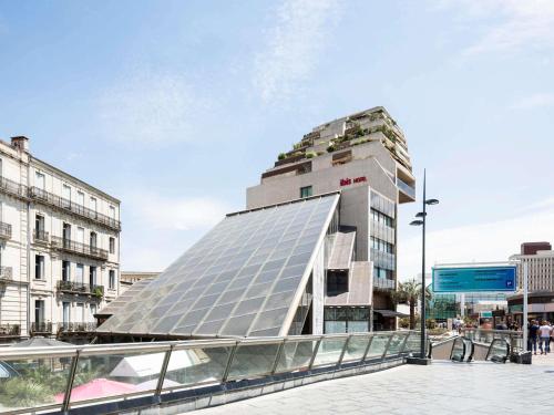 a building with a glass facade in a city at ibis Montpellier Centre Comedie in Montpellier