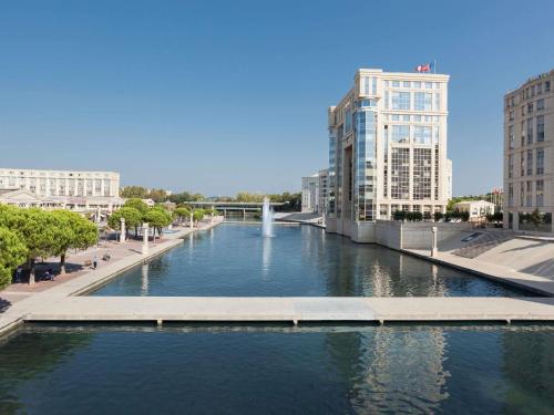 a river in a city with buildings and a bridge at ibis Montpellier Centre Comedie in Montpellier