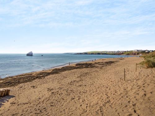 a sandy beach with a rock in the water at 2 bed property in Thurlestone WDELV in Thurlestone