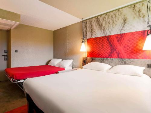 a hotel room with two beds and a red couch at ibis Carcassonne Est la Cité in Carcassonne