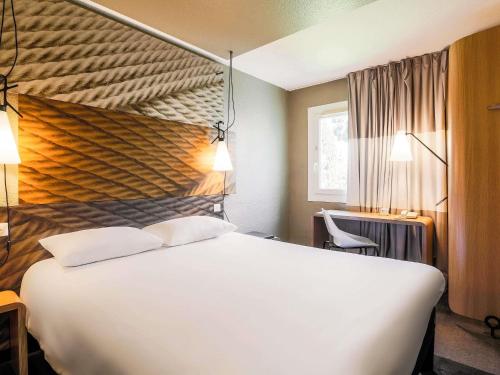 a bedroom with a large white bed with two pillows at ibis Carcassonne Est la Cité in Carcassonne