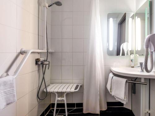 a white bathroom with a shower and a sink at ibis Carcassonne Est la Cité in Carcassonne