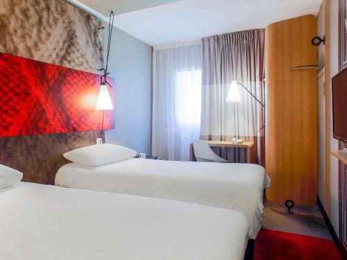 a hotel room with two beds and a window at ibis Carcassonne Est la Cité in Carcassonne