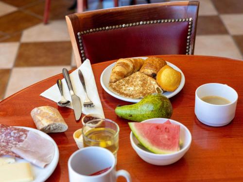 a wooden table with plates of food on it at ibis Carcassonne Est la Cité in Carcassonne