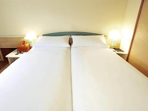 two large beds in a hotel room with two lamps at ibis Chambery in Chambéry