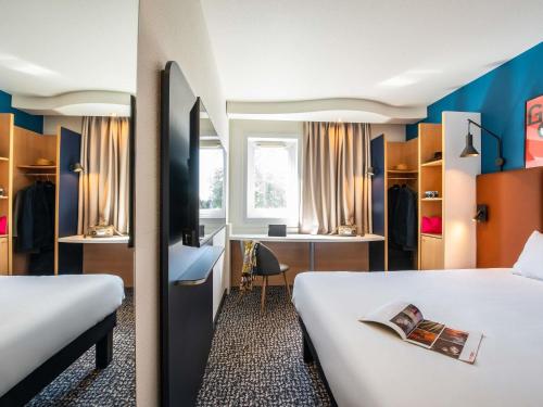 a hotel room with two beds and a desk at ibis Chalon Sur Saone Nord in Chalon-sur-Saône