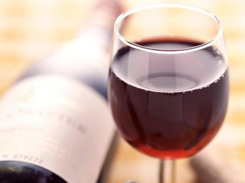 a glass of red wine next to a bottle at ibis Chalon Sur Saone Nord in Chalon-sur-Saône