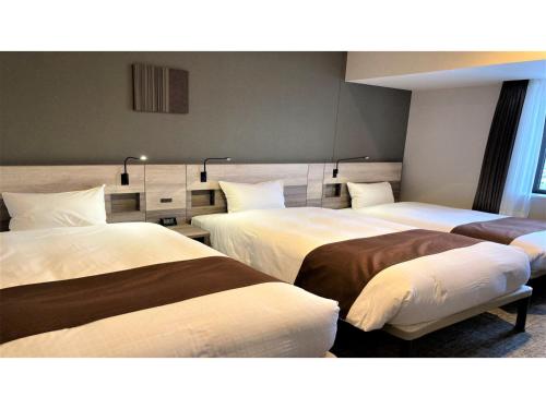 a hotel room with three beds in it at Smile Hotel Premium Hakodate Goryokaku - Vacation STAY 97564v in Hakodate