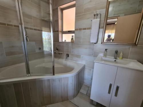 a bathroom with a tub and a sink at DuneSide Guesthouse in Richards Bay