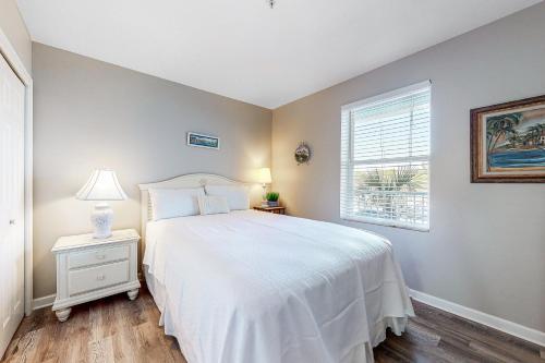a bedroom with a white bed and a window at Grand Caribbean 104 in Orange Beach