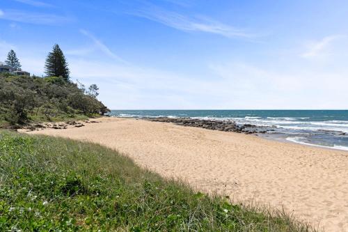 una playa de arena con el océano al fondo en Beachside Bungalow on Shelly Beach, en Caloundra