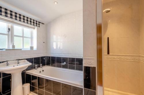 a bathroom with a bath tub and a sink at Watts Cottage in Upton